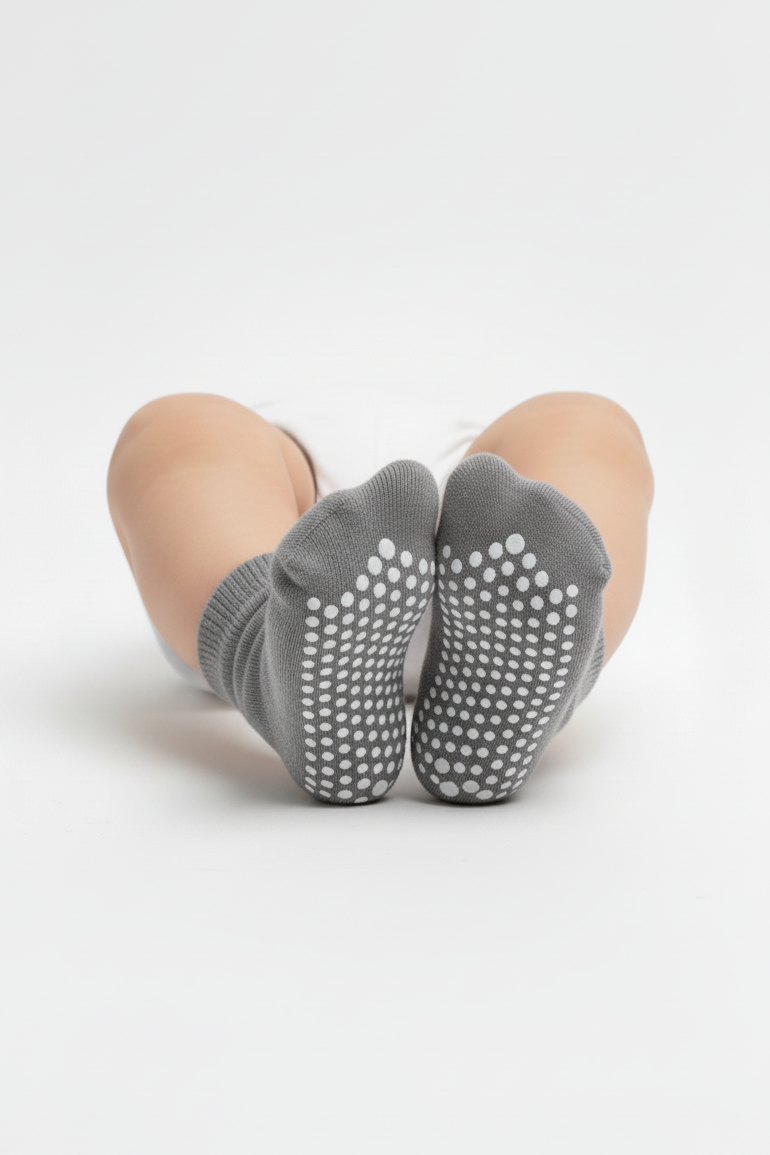 Gray grip socks worn by a baby on a white background