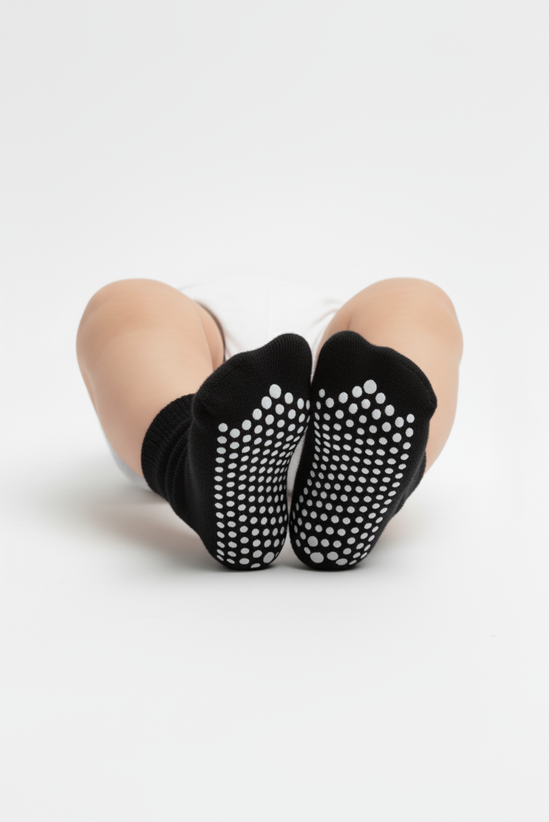 Black socks with white dots worn by a baby on a light gray background
