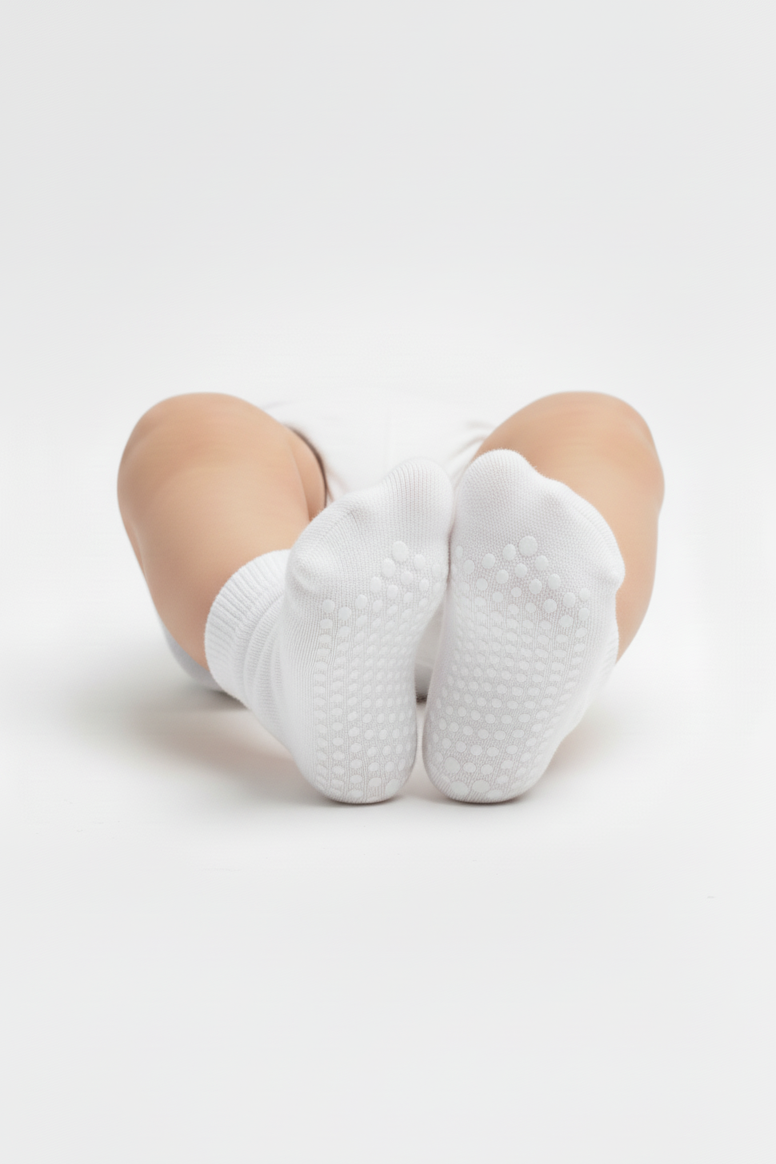 White socks with textured sole worn by a person on a light gray background